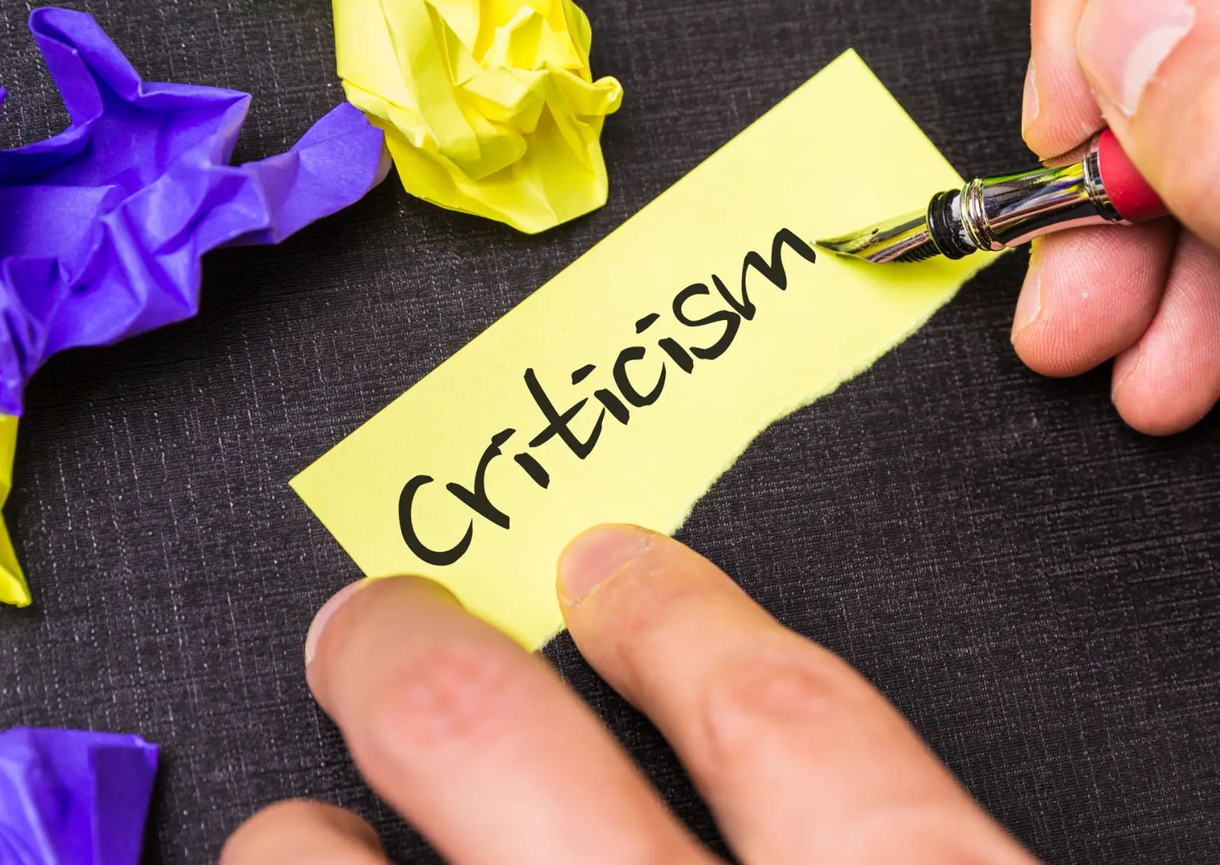 A graphic of a yellow piece of paper with the word "criticism."