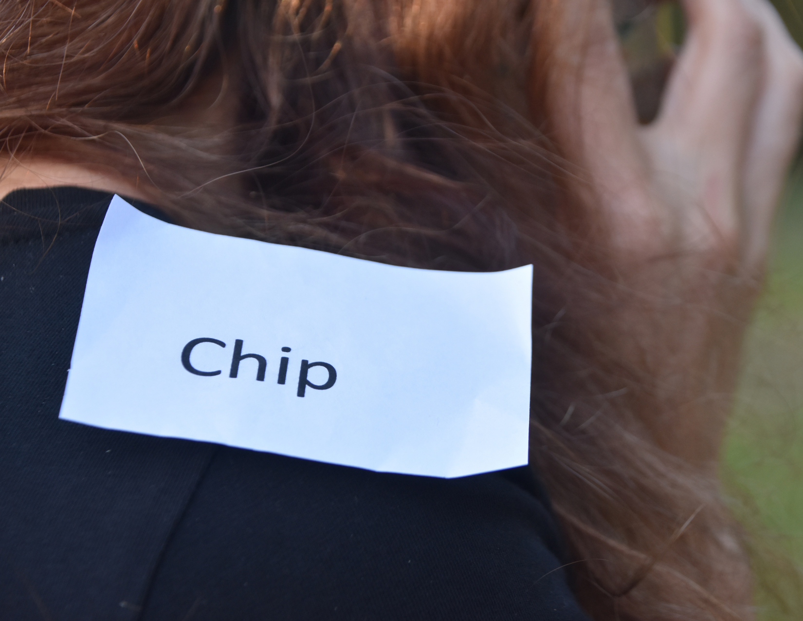 A picture of a girl with paper with the word "chip" on her shoulder to signify the phrase "a chip on your shoulder"